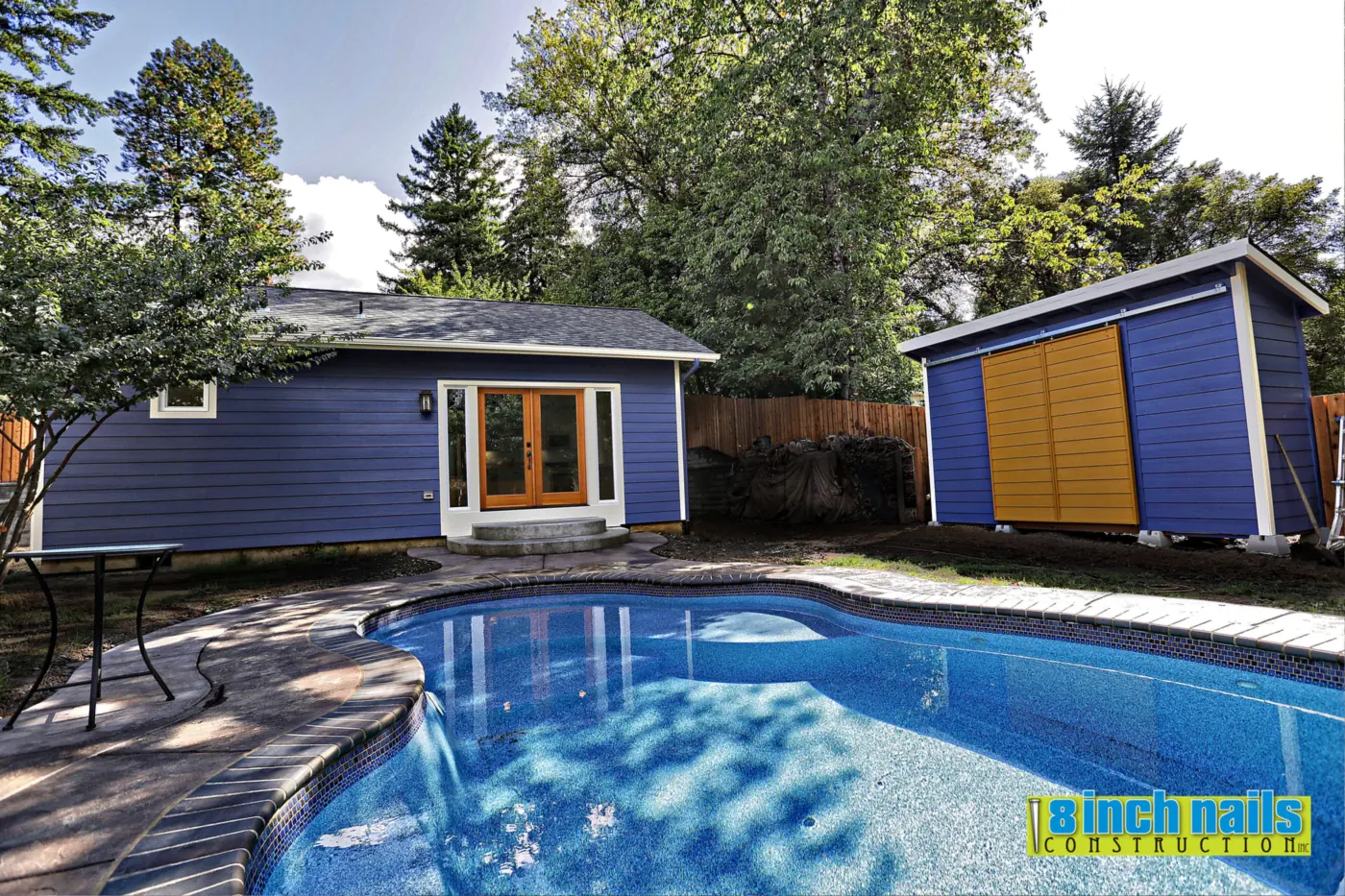 Detached ADU in Tigard, OR — navy HardiePlank siding and a matching storage shed beside the pool
