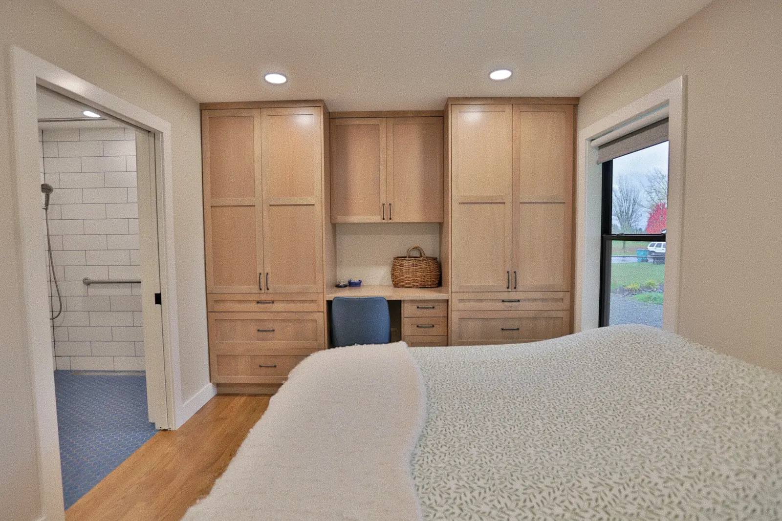 Bedroom with built-in white oak storage and a pocket door through to the accessible bath