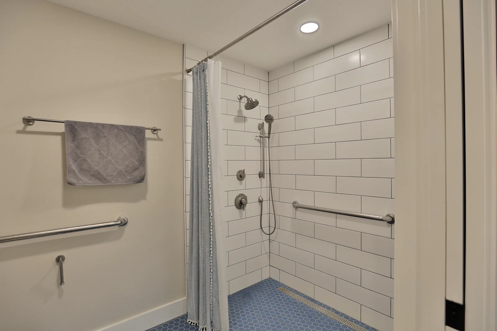 Roll-in shower with no threshold, grab bars and a handheld sprayer, built for accessibility