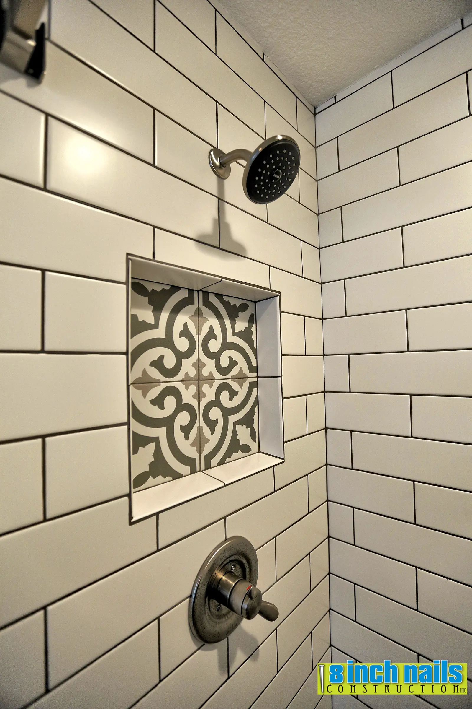 Subway tile shower with a recessed niche tiled in the patterned floor tile