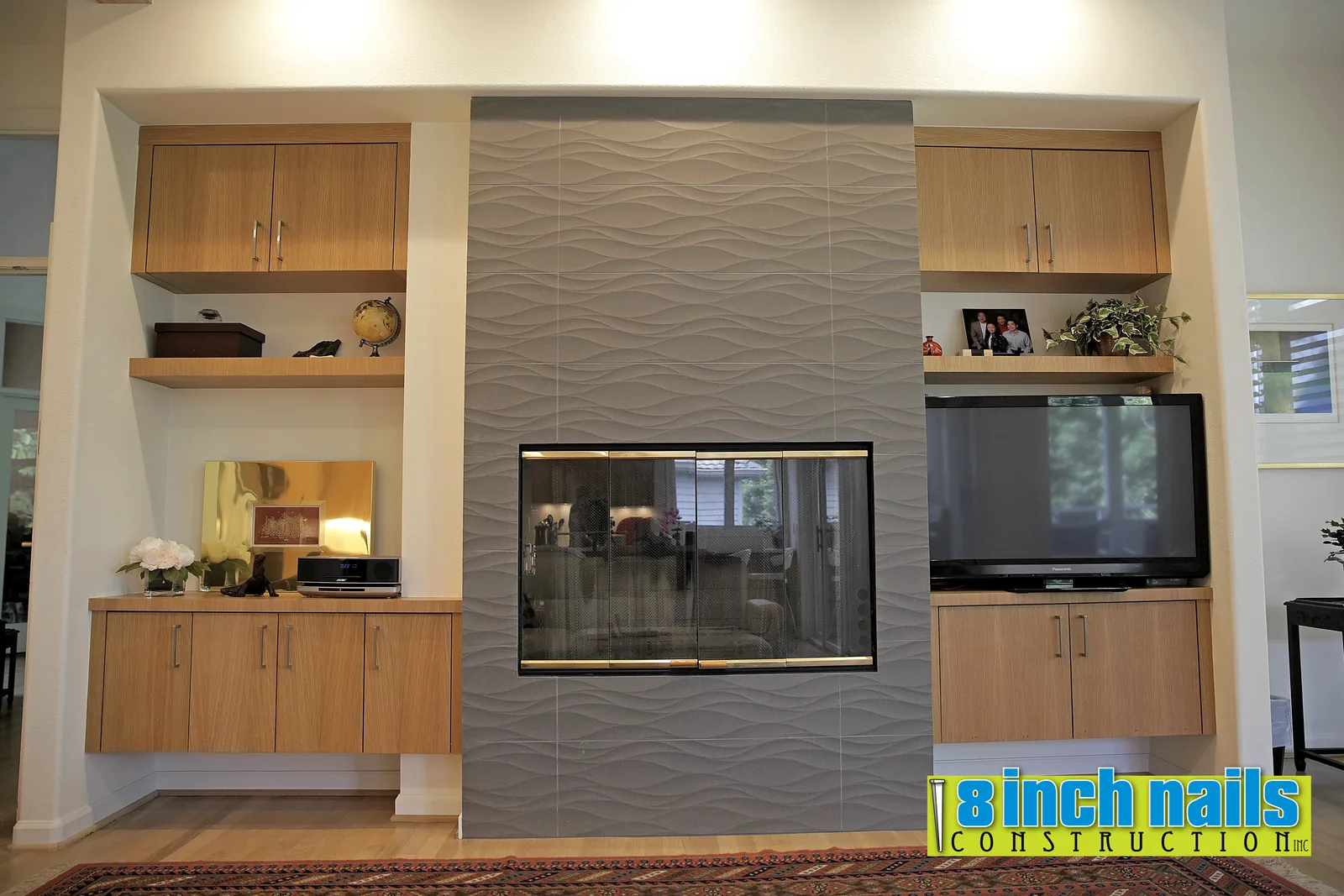 Fireplace wall in wave-textured tile, floor to ceiling, flanked by white oak built-ins